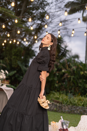 Vestido negro y zapatos de trenza dorados.