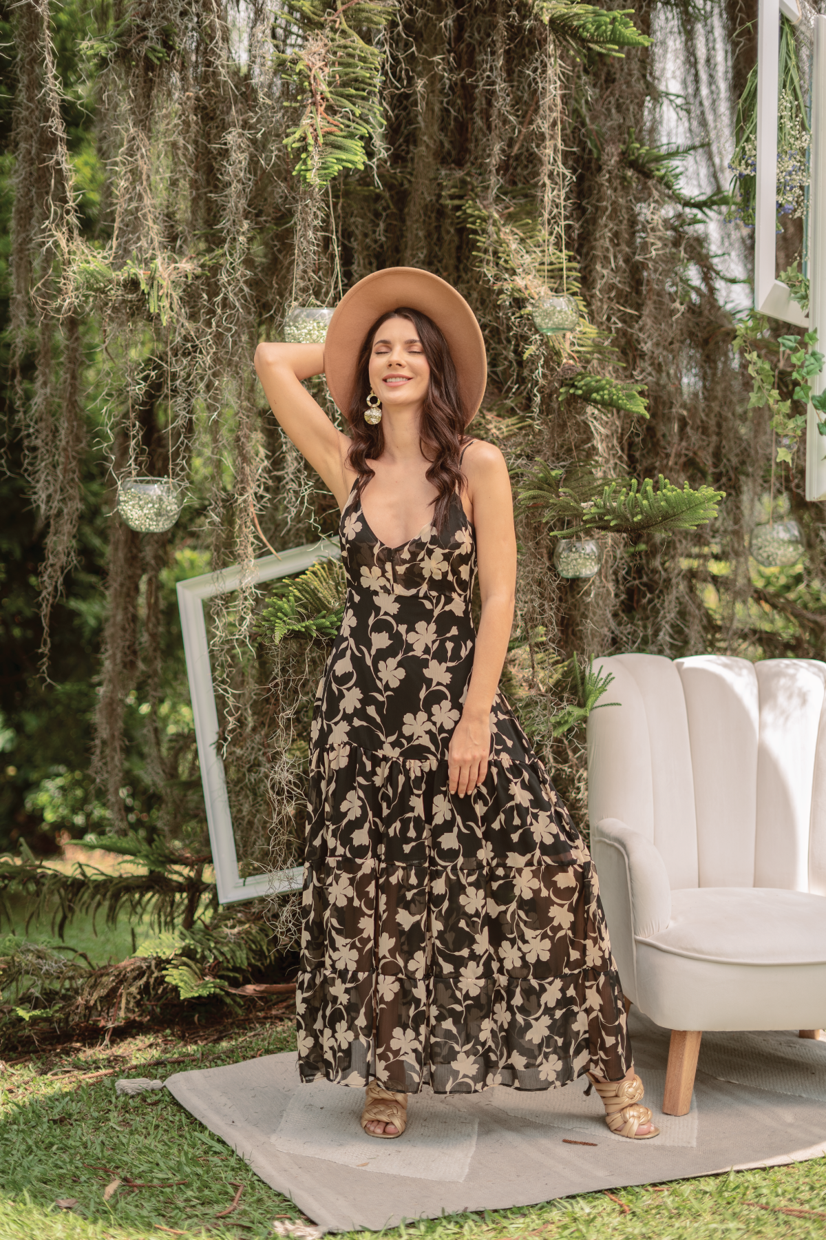 Vestido de tiras, largo y negro, con tacones dorados.